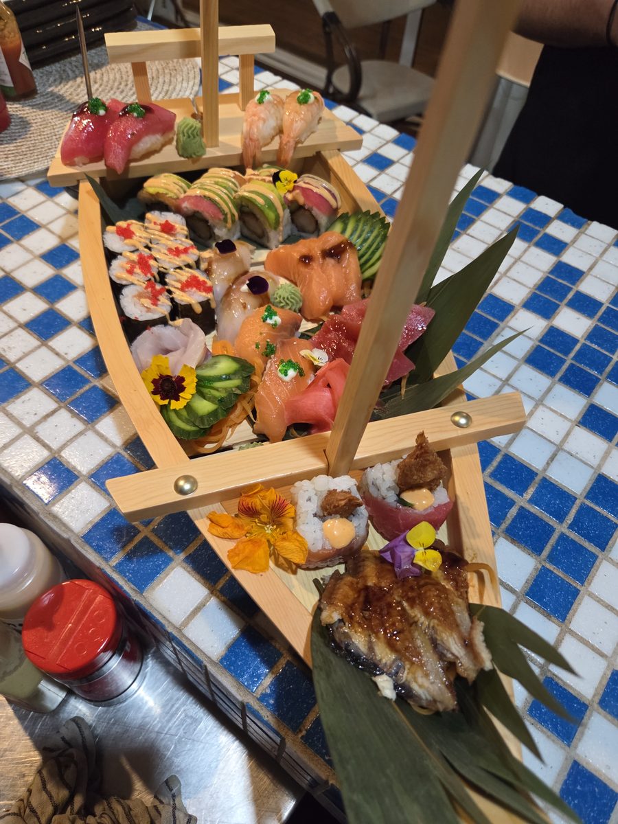 A wooden sushi boat loaded with nigiri, maki and sashimi